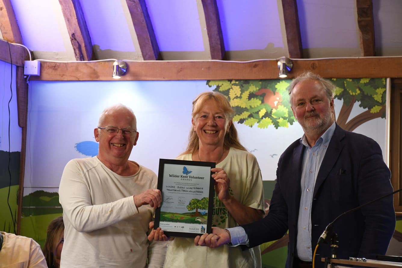 A man and two women holding a plaque